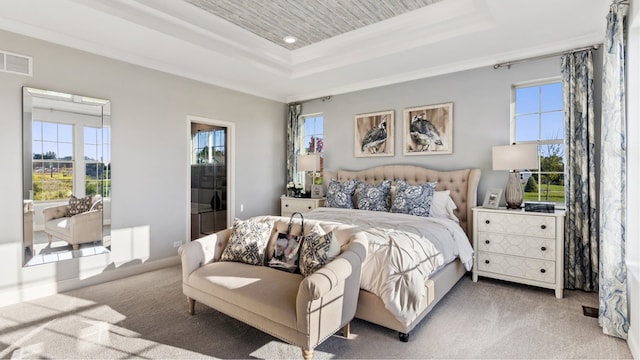 carpeted bedroom with ornamental molding and a tray ceiling