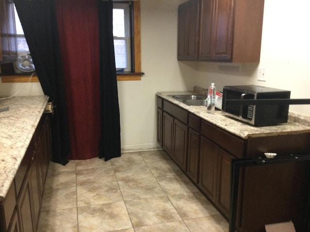 kitchen with light stone counters, sink, and dark brown cabinetry