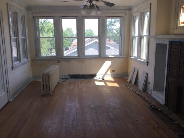 unfurnished sunroom featuring radiator and ceiling fan