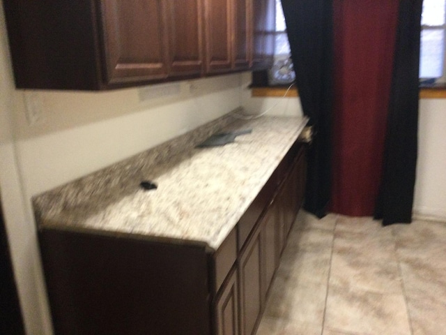 kitchen featuring light tile patterned flooring and dark brown cabinetry