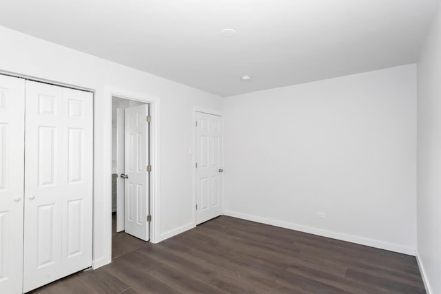 unfurnished bedroom with dark hardwood / wood-style flooring and a closet