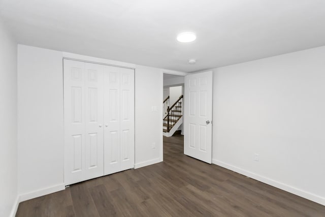 unfurnished bedroom with dark hardwood / wood-style flooring and a closet