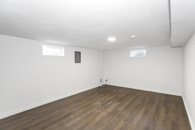 basement featuring dark hardwood / wood-style floors, a healthy amount of sunlight, and electric panel