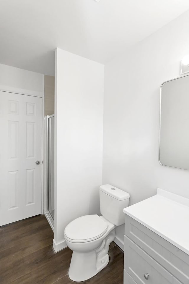 bathroom with vanity, hardwood / wood-style flooring, toilet, and a shower with shower door