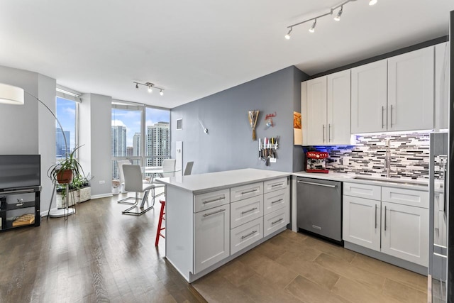 kitchen with stainless steel dishwasher, white cabinetry, kitchen peninsula, and backsplash