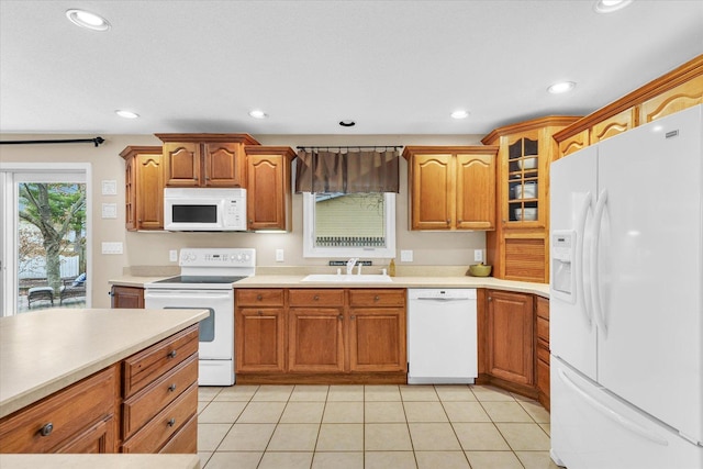 kitchen featuring sink, light tile patterned flooring, and white appliances