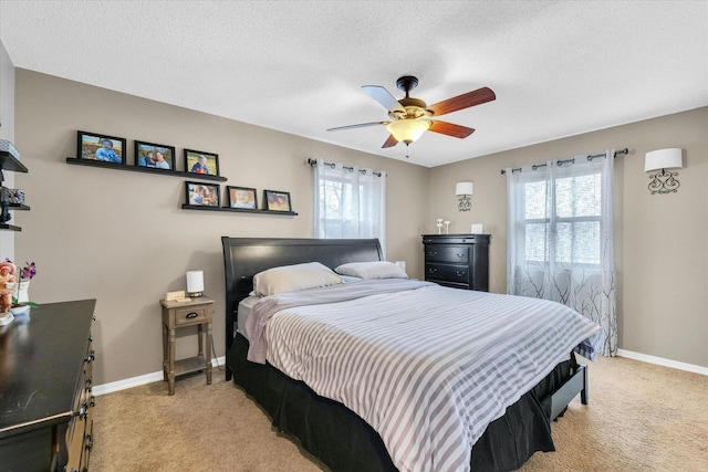 carpeted bedroom featuring ceiling fan, a textured ceiling, and multiple windows