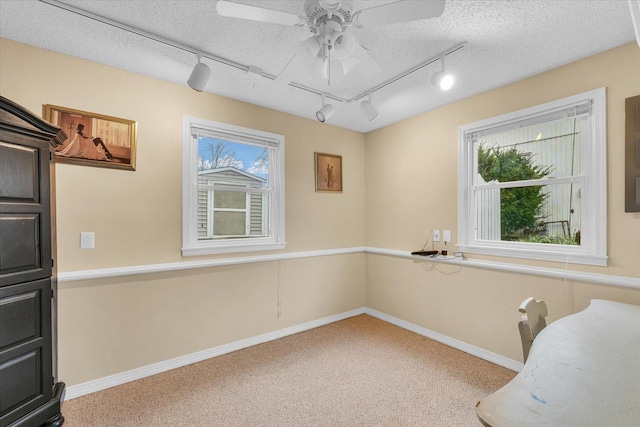 carpeted office with ceiling fan, track lighting, and a textured ceiling