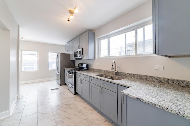 kitchen featuring gray cabinetry, light stone countertops, sink, and appliances with stainless steel finishes