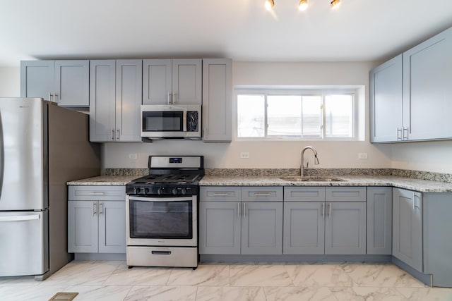 kitchen with light stone countertops, stainless steel appliances, gray cabinetry, and sink