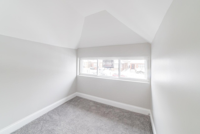 carpeted empty room with lofted ceiling