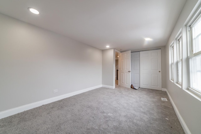 unfurnished bedroom with carpet, a closet, and multiple windows