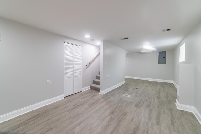 basement featuring light wood-type flooring and electric panel