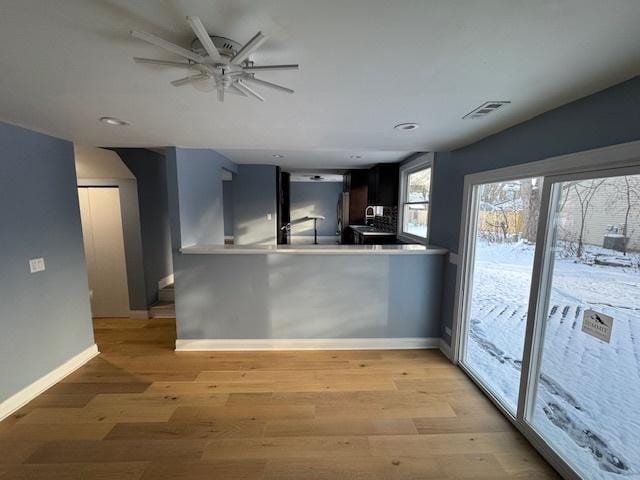 kitchen with stainless steel refrigerator, ceiling fan, kitchen peninsula, and light hardwood / wood-style floors