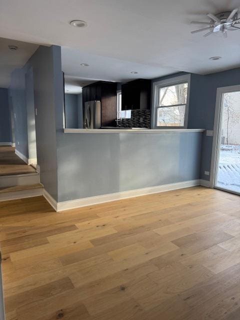 kitchen with hardwood / wood-style flooring, ceiling fan, stainless steel fridge, tasteful backsplash, and kitchen peninsula