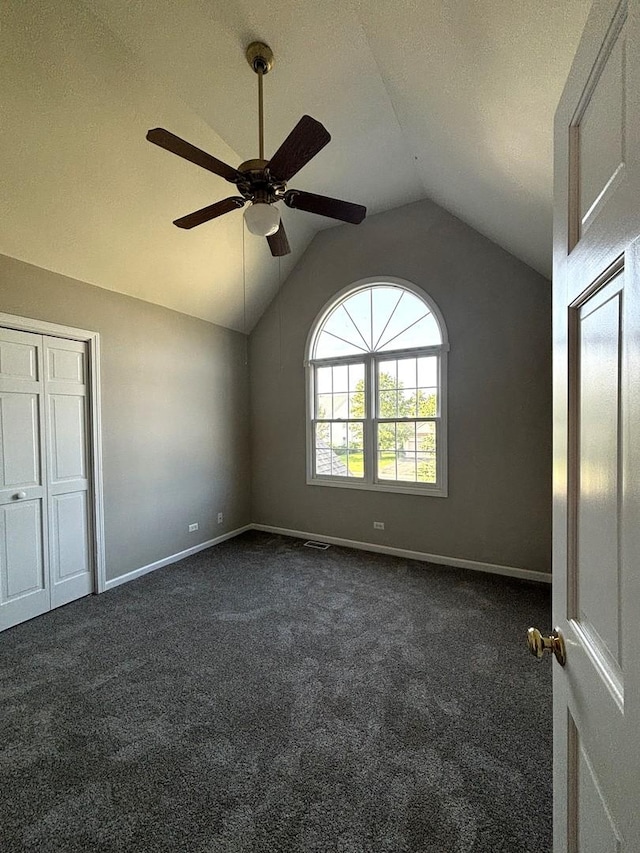 unfurnished bedroom featuring a textured ceiling, ceiling fan, dark carpet, and vaulted ceiling