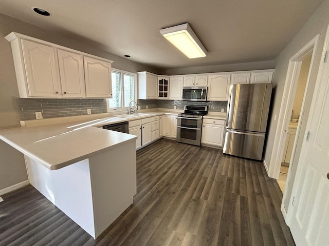 kitchen with sink, kitchen peninsula, dark hardwood / wood-style flooring, white cabinetry, and stainless steel appliances