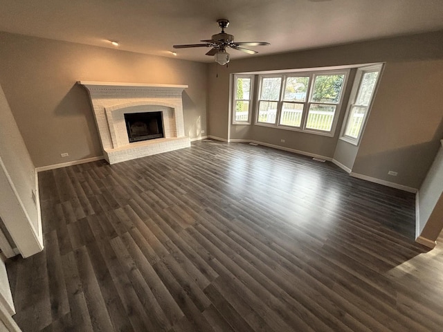 unfurnished living room featuring ceiling fan, dark hardwood / wood-style floors, and a brick fireplace