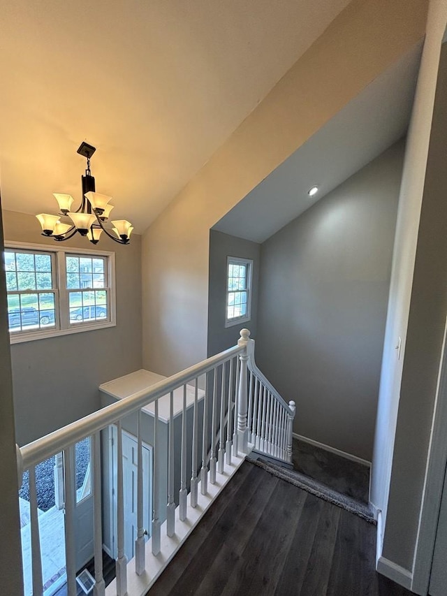 stairs with a chandelier, hardwood / wood-style floors, a healthy amount of sunlight, and vaulted ceiling