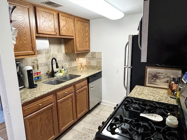 kitchen featuring tasteful backsplash, black range with gas stovetop, sink, light tile patterned floors, and dishwasher