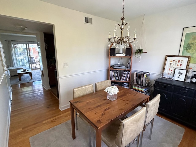 dining area featuring hardwood / wood-style flooring and an inviting chandelier