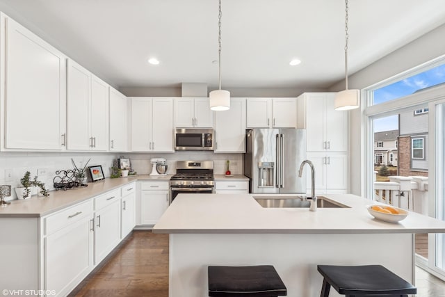 kitchen with pendant lighting, sink, tasteful backsplash, white cabinetry, and stainless steel appliances