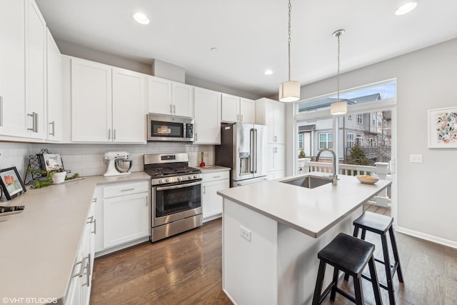 kitchen with a kitchen island with sink, sink, appliances with stainless steel finishes, tasteful backsplash, and white cabinetry