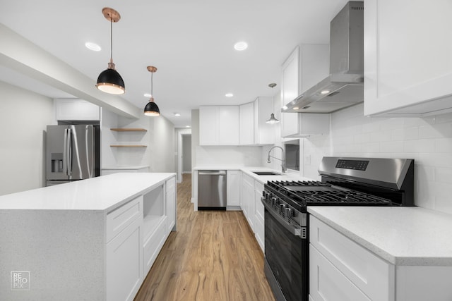 kitchen featuring white cabinets, light wood-type flooring, wall chimney range hood, and appliances with stainless steel finishes