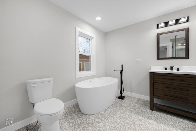 bathroom with a washtub, vanity, and toilet