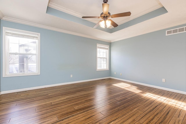 spare room featuring a tray ceiling, crown molding, ceiling fan, and dark wood-type flooring