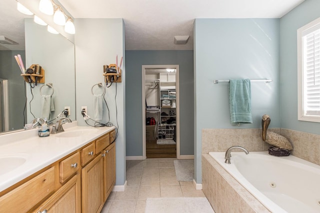 bathroom with tile patterned floors, tiled bath, and vanity