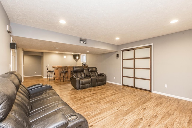 living room with bar area, light hardwood / wood-style flooring, and a textured ceiling