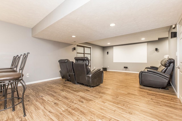 home theater room with light hardwood / wood-style flooring and a textured ceiling