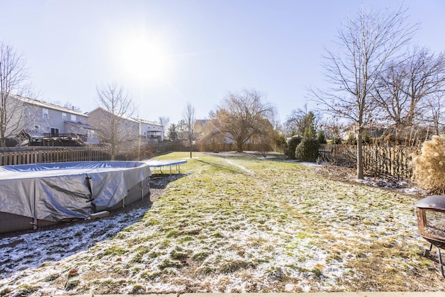 view of yard with a trampoline and a covered pool