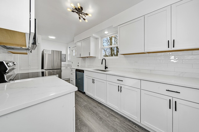 kitchen with white cabinetry, sink, light stone counters, wood-type flooring, and appliances with stainless steel finishes