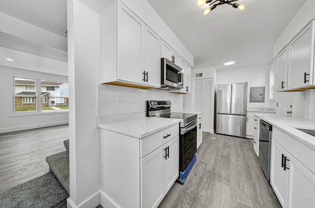 kitchen featuring white cabinets, light wood-type flooring, stainless steel appliances, and backsplash