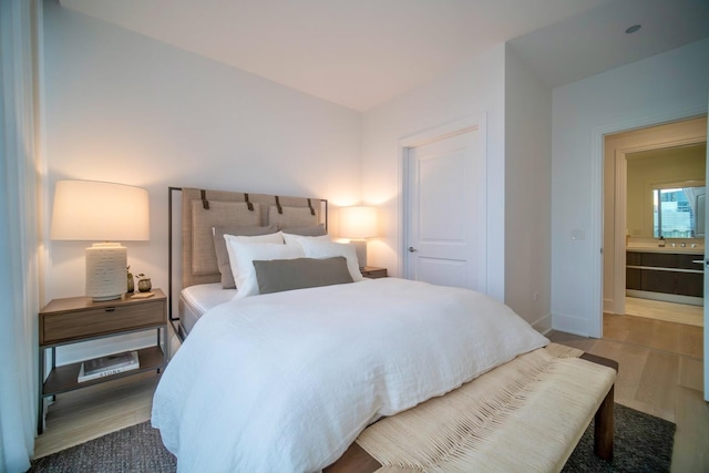 bedroom with hardwood / wood-style floors, a closet, and ensuite bath