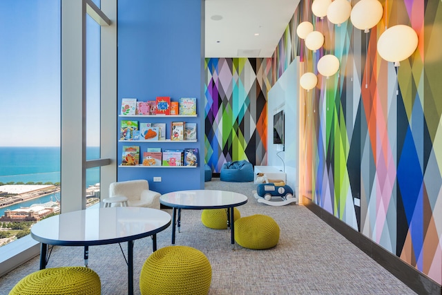 game room featuring carpet flooring and a water view