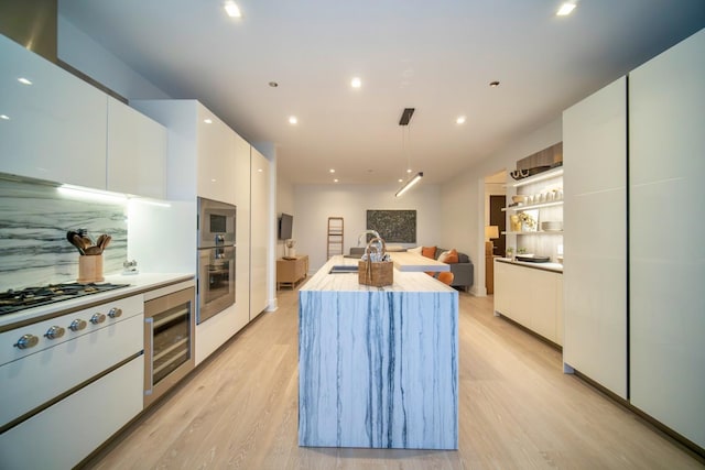 kitchen with a center island with sink, white cabinetry, tasteful backsplash, and light hardwood / wood-style flooring