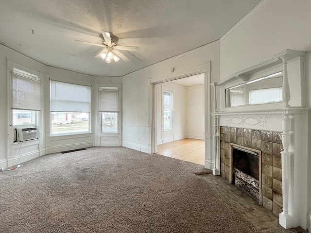 unfurnished living room featuring carpet flooring, a textured ceiling, ceiling fan, and a tiled fireplace