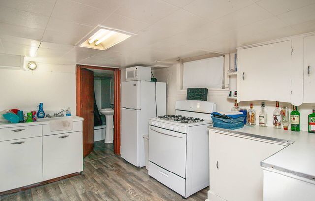 kitchen with white cabinets, wood-type flooring, and white appliances