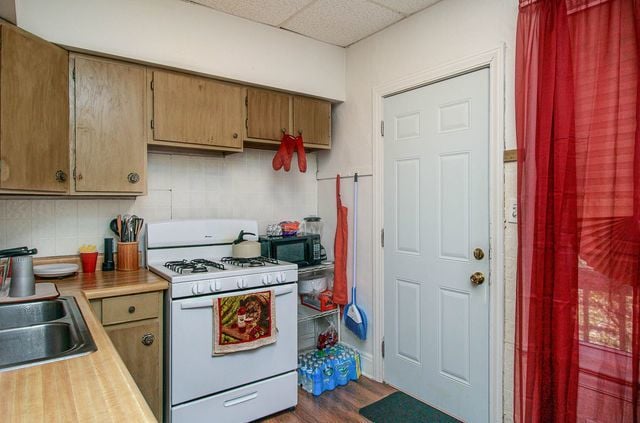 kitchen featuring a drop ceiling, backsplash, sink, dark hardwood / wood-style floors, and gas range gas stove