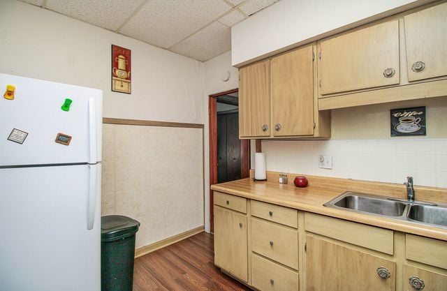 kitchen with dark hardwood / wood-style flooring, a paneled ceiling, sink, light brown cabinets, and white fridge