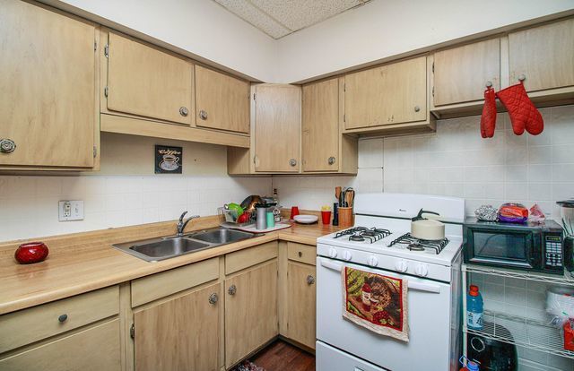 kitchen featuring white range with gas stovetop, light brown cabinetry, and sink