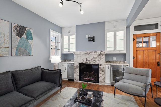 living room featuring hardwood / wood-style flooring, a premium fireplace, beverage cooler, and track lighting