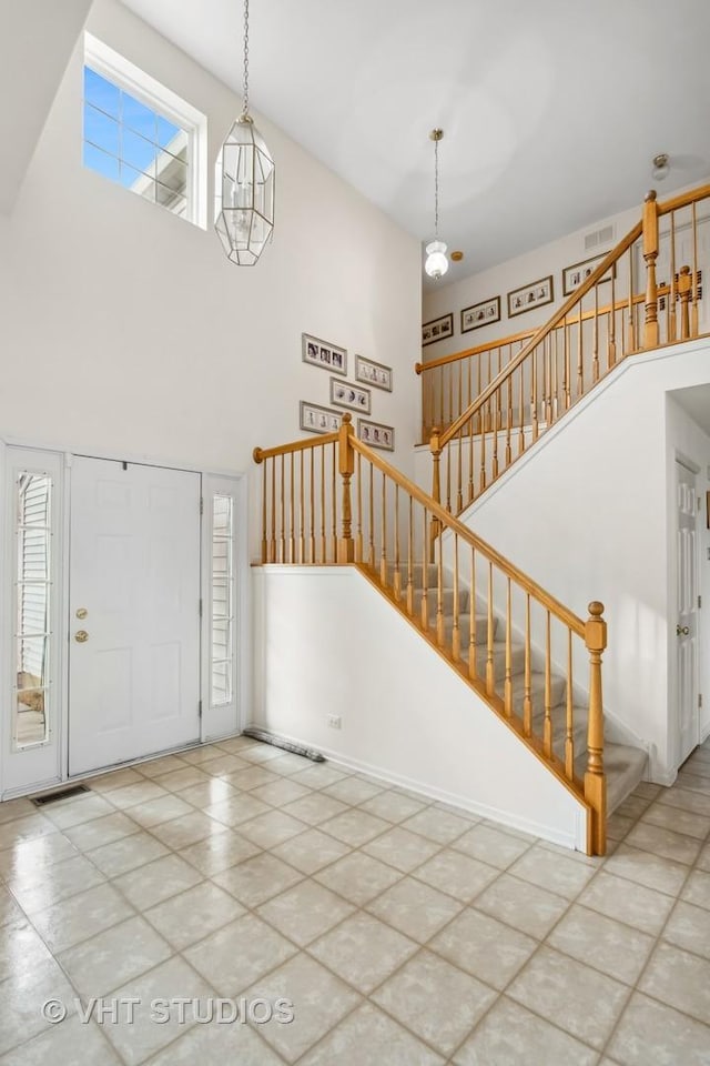 foyer entrance featuring a towering ceiling and an inviting chandelier