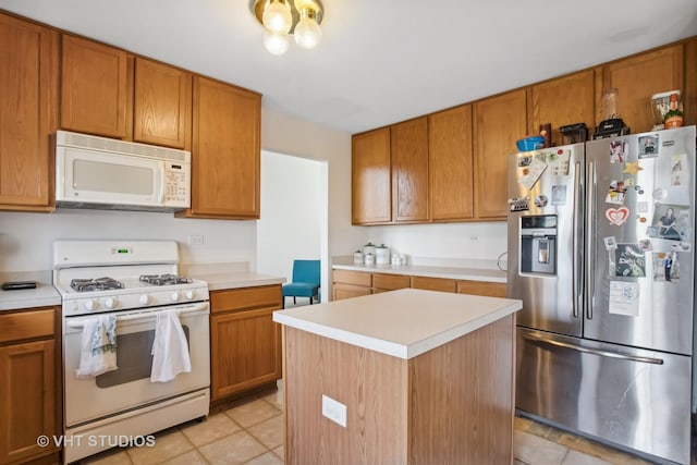 kitchen featuring light tile patterned floors, white appliances, and a kitchen island