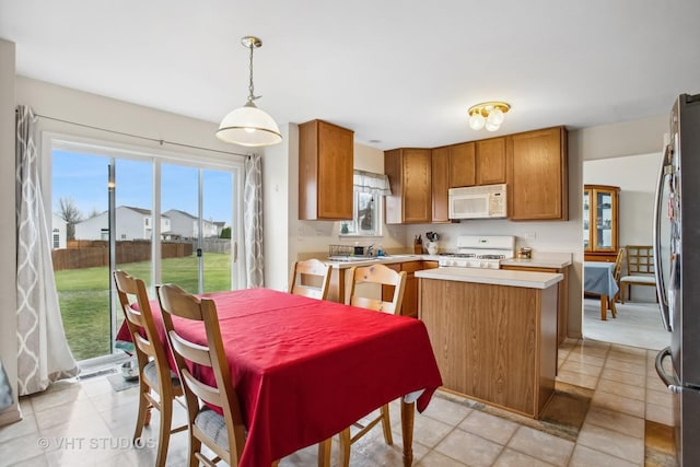 kitchen featuring light tile patterned floors, white appliances, a center island, and hanging light fixtures