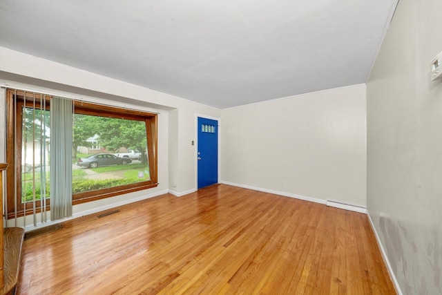 empty room featuring hardwood / wood-style floors and a baseboard heating unit