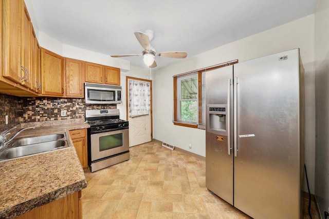 kitchen with decorative backsplash, appliances with stainless steel finishes, ceiling fan, and sink